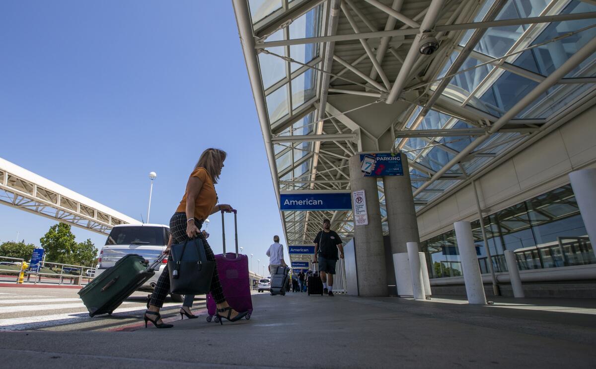 A woman with a suitcase heads into a terminal at Ontario International Airport prepandemic.