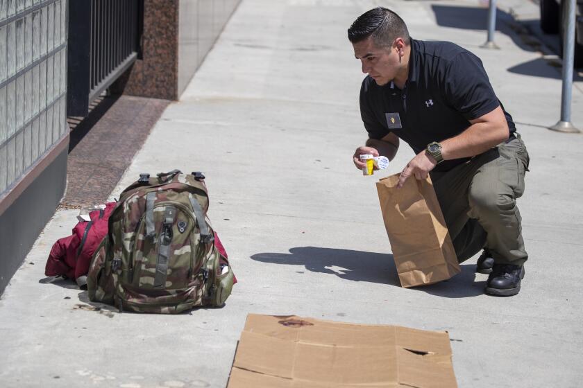 LOS ANGELES, CALIF. -- SUNDAY, SEPTEMBER 1, 2019: Investigator Adrian Munoz, of the Los Angeles County Medical Examiner-Coroner, remove medicine, sleeping bag and backpack belonging to an African-American homeless man in his 60Õs that was found laying dead with his sleeping bag and backpack on a piece of cardboard on the sidewalk near the intersection of Massachusetts Ave. and Sepulveda Bl. in Los Angeles, Calif., on Sept. 1, 2019. (Allen J. Schaben / Los Angeles Times)