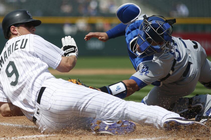 The Colorado Rockies' DJ LeMahieu avoids the tag by Dodgers catcher Carlos Ruiz to score on a double by Nolan Arenado in the first inning of the first game of a doubleheader.