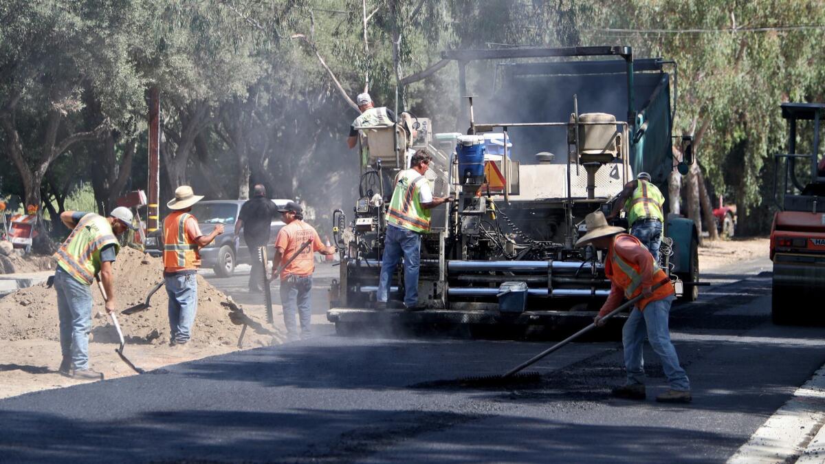 Construction workers put down new rubberized asphalt on Gould Avenue near Paradise Canyon Elementary School on Tuesday, Aug. 14, 2018.