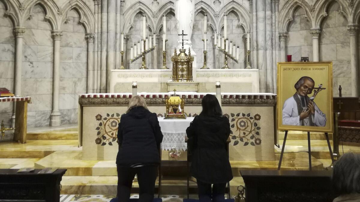 Two women pray in front a container bearing the 150-year-old heart of French priest St. John Vianney on Saturday at St. Patrick's Cathedral in New York. The heart is being toured throughout the United States.