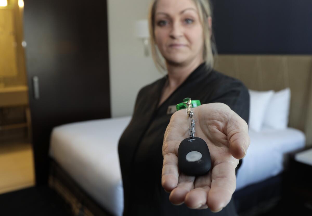 Rani Accettola, a housekeeper at the Embassy Suites by Hilton hotel in Seattle's Pioneer Square neighborhood, holds a device that lets her push a button and summon help if she is in a threatening situation.