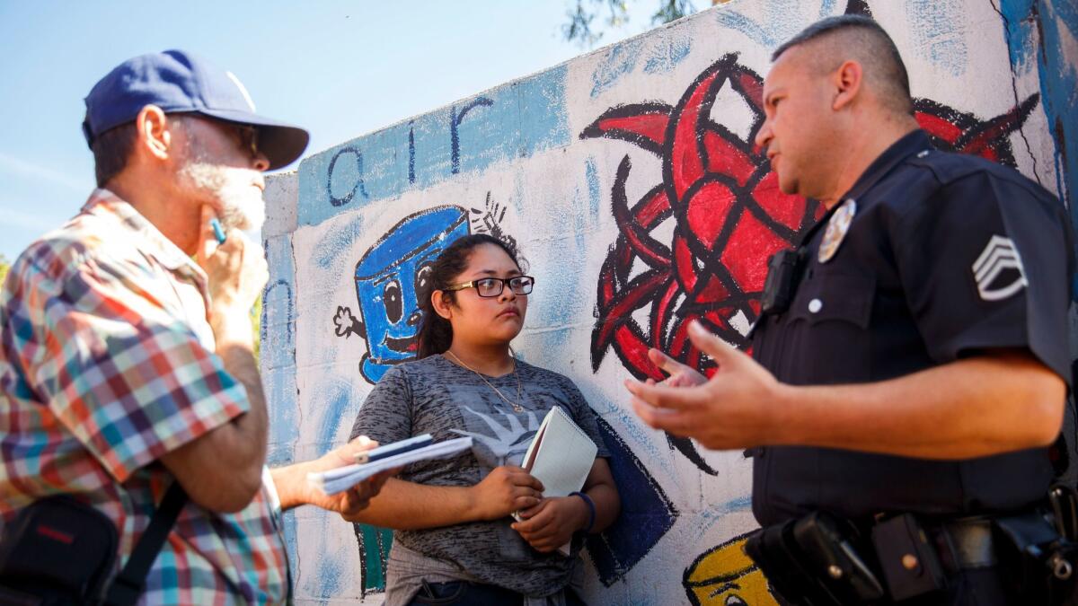 Senior Editor Antonio Mejias-Rentas, left, and student reporter Kimberly Gallardo, 16, of the Boyle Heights Beat newspaper interview a Los Angeles police sergeant for a report on a swap meet at the Ramona Gardens housing project.
