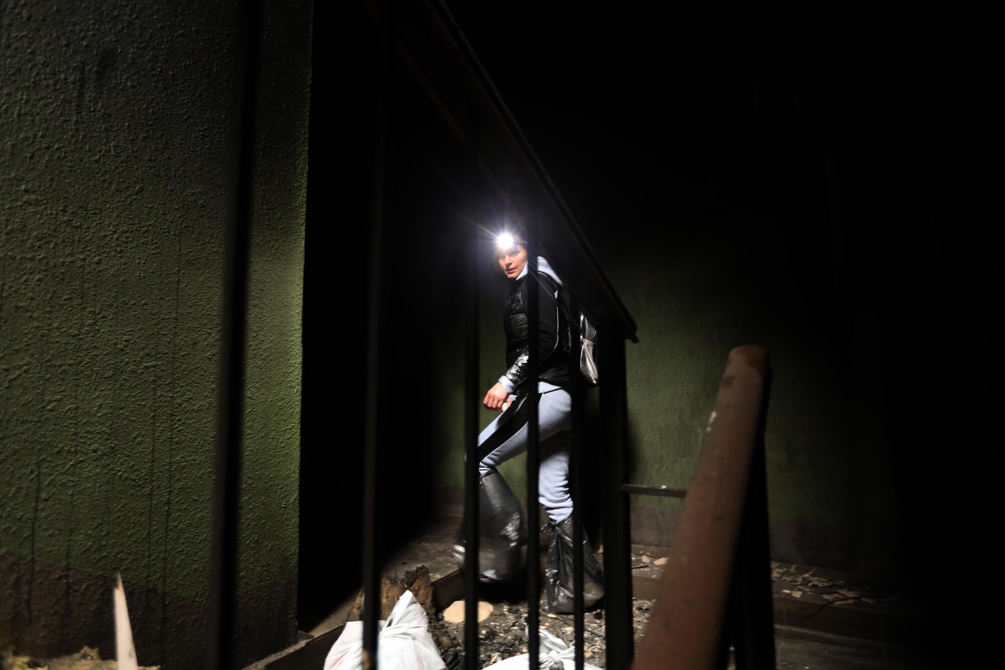 A woman wearing a headlamp in a damaged building 