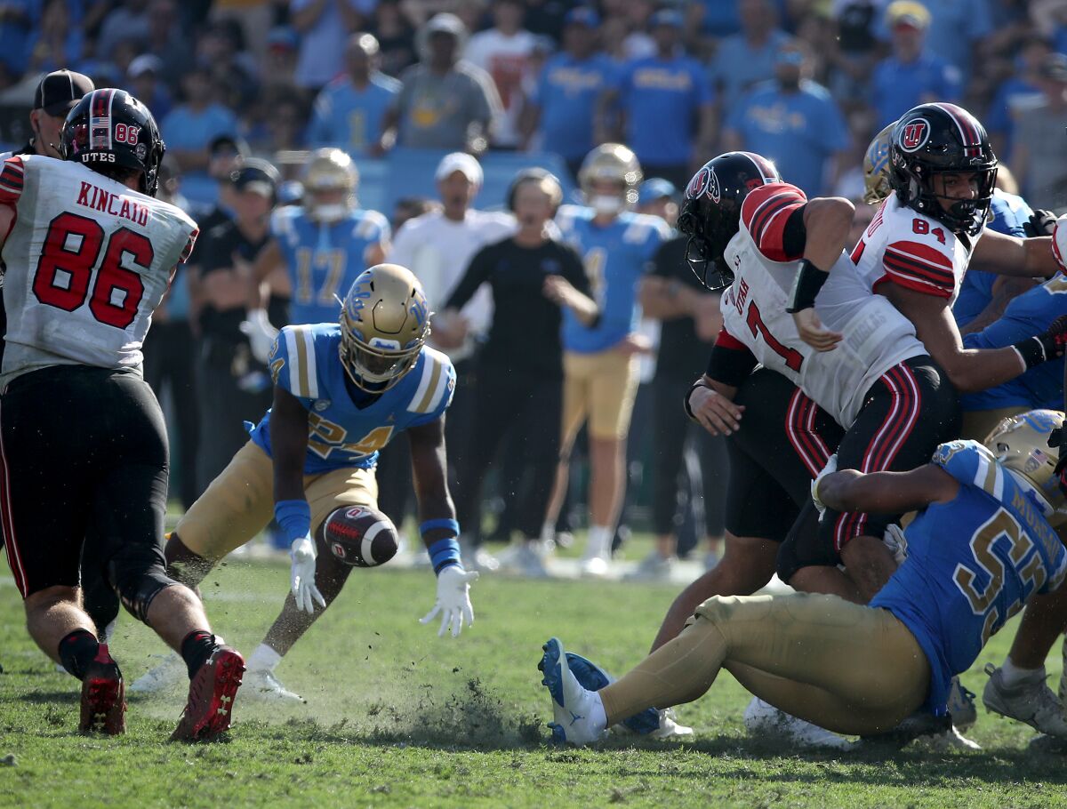 UCLA cornerback Jaylin Davies scoops up a fumble by Utah quarterback Cameron Rising.