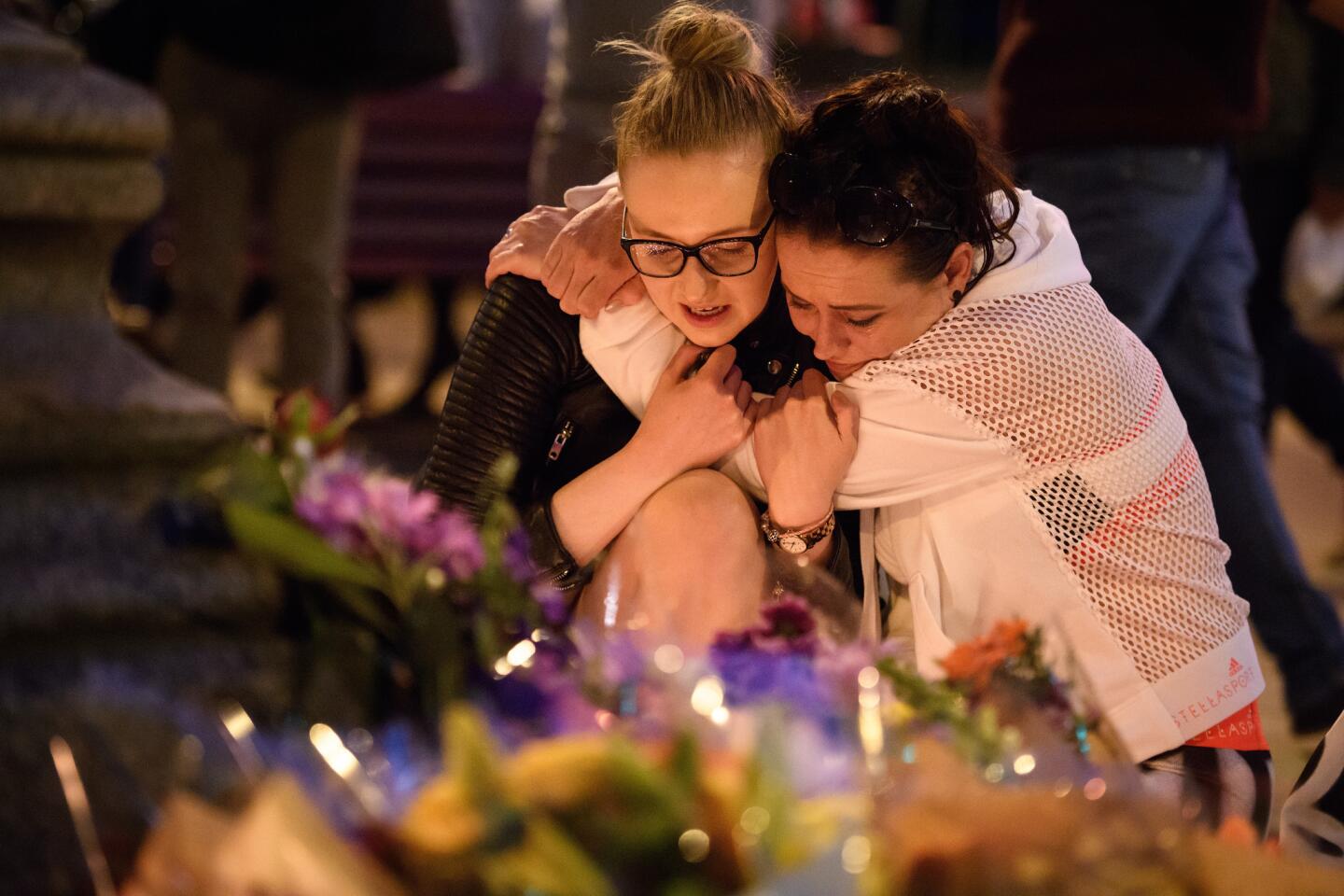 A woman is consoled as she looks at the floral tributes after an evening vigil outside the Town Hall on May 23, 2017, in Manchester, England. An explosion occurred at Manchester Arena as concertgoers were leaving an Ariana Grande performance.