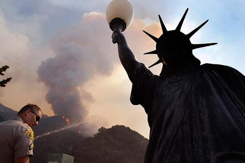 A Los Angeles County sheriff's deputy stands near a facsimile of the Statue of Liberty in La Crescenta.