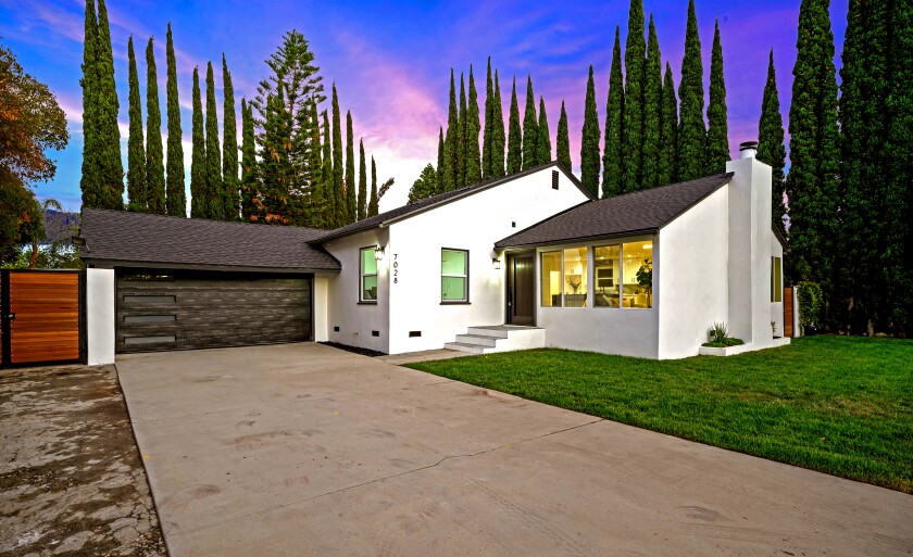 A small white home with a dark-colored garage door.