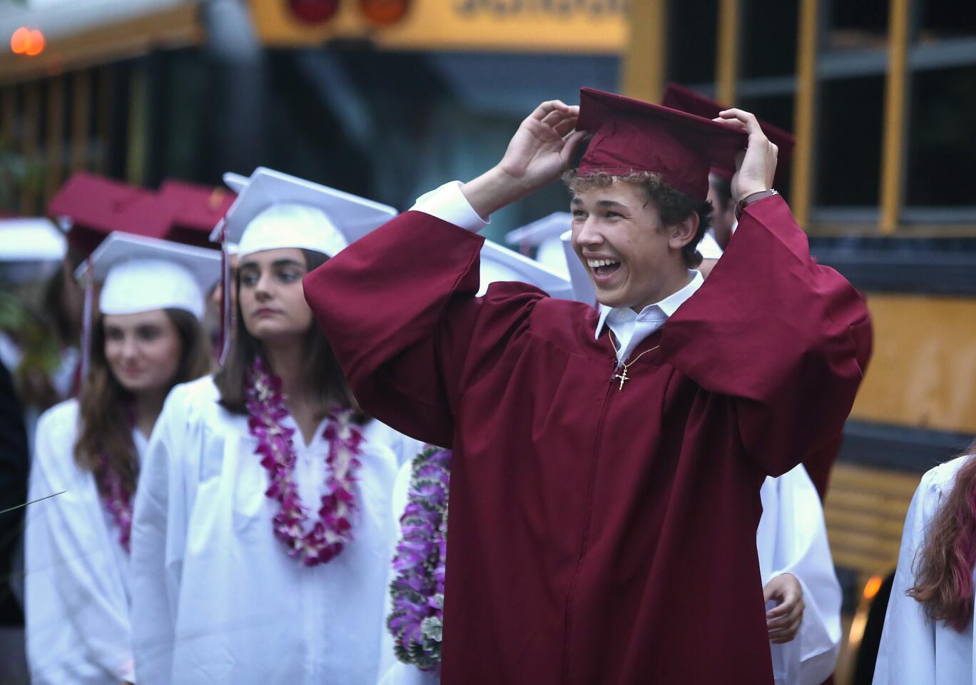 Graduate Jake Mastrobuti adjusts his cap as he arrives at the Laguna Beach High School commencement ceremony Thursday at the Irvine Bowl on the Festival of Arts grounds.
