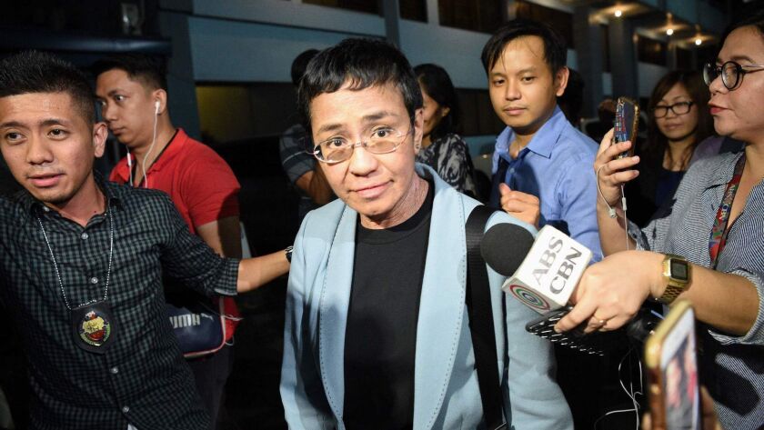 Philippine journalist Maria Ressa, center, is escorted into National Bureau of Investigations headquarters in Manila after being arrested on a charge of cyber libel on Feb. 13.