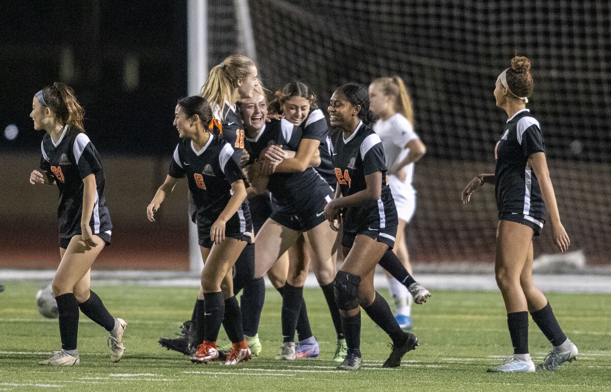 Huntington Beach teammates mob Kyley Asheim after she scores a goal against Corona del Mar.