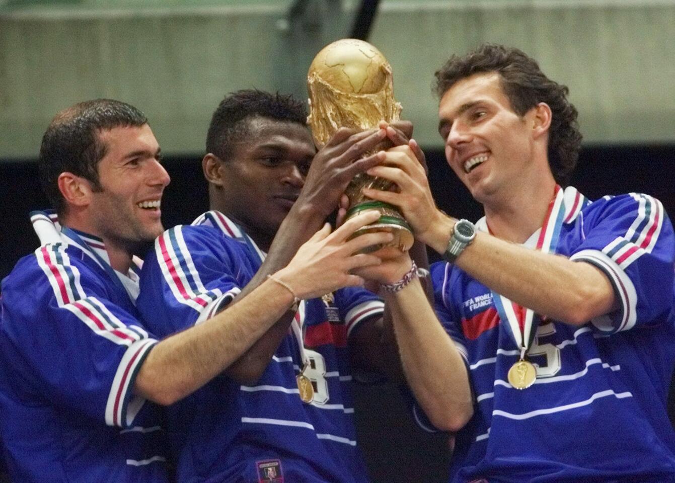 FILE - In this Sunday, July 12, 1998 file photo, French teammates from left, Zinedine Zidane, Marcel Desailly and Laurent Blanc hold the soccer World Cup after France defeated Brazil 3-0 in the World Cup final soccer match, at the Stade de France in Saint Denis. (AP Photo/Michel Euler, File)