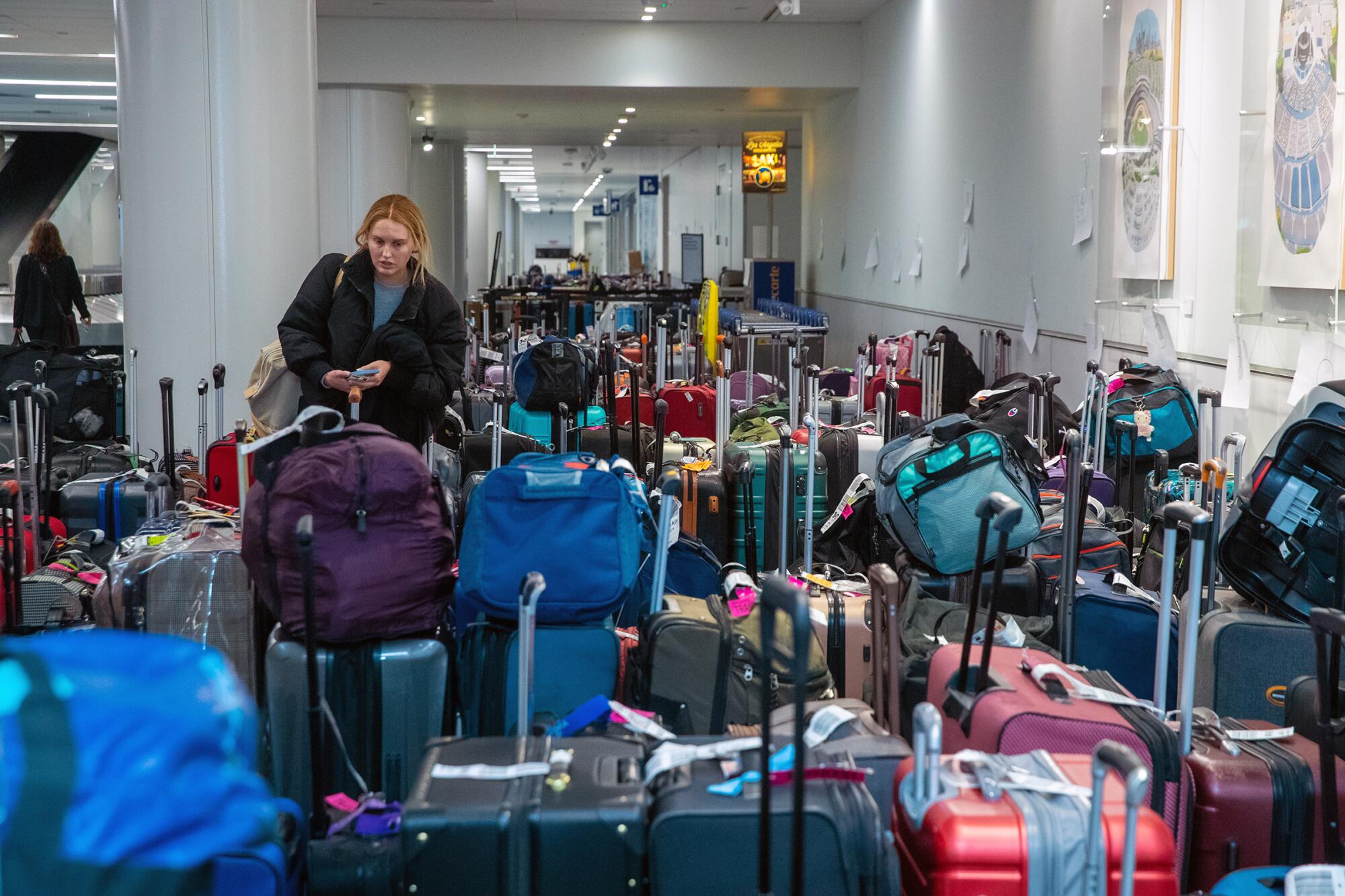 A woman seeks out her luggage among dozens of bags at LAX.