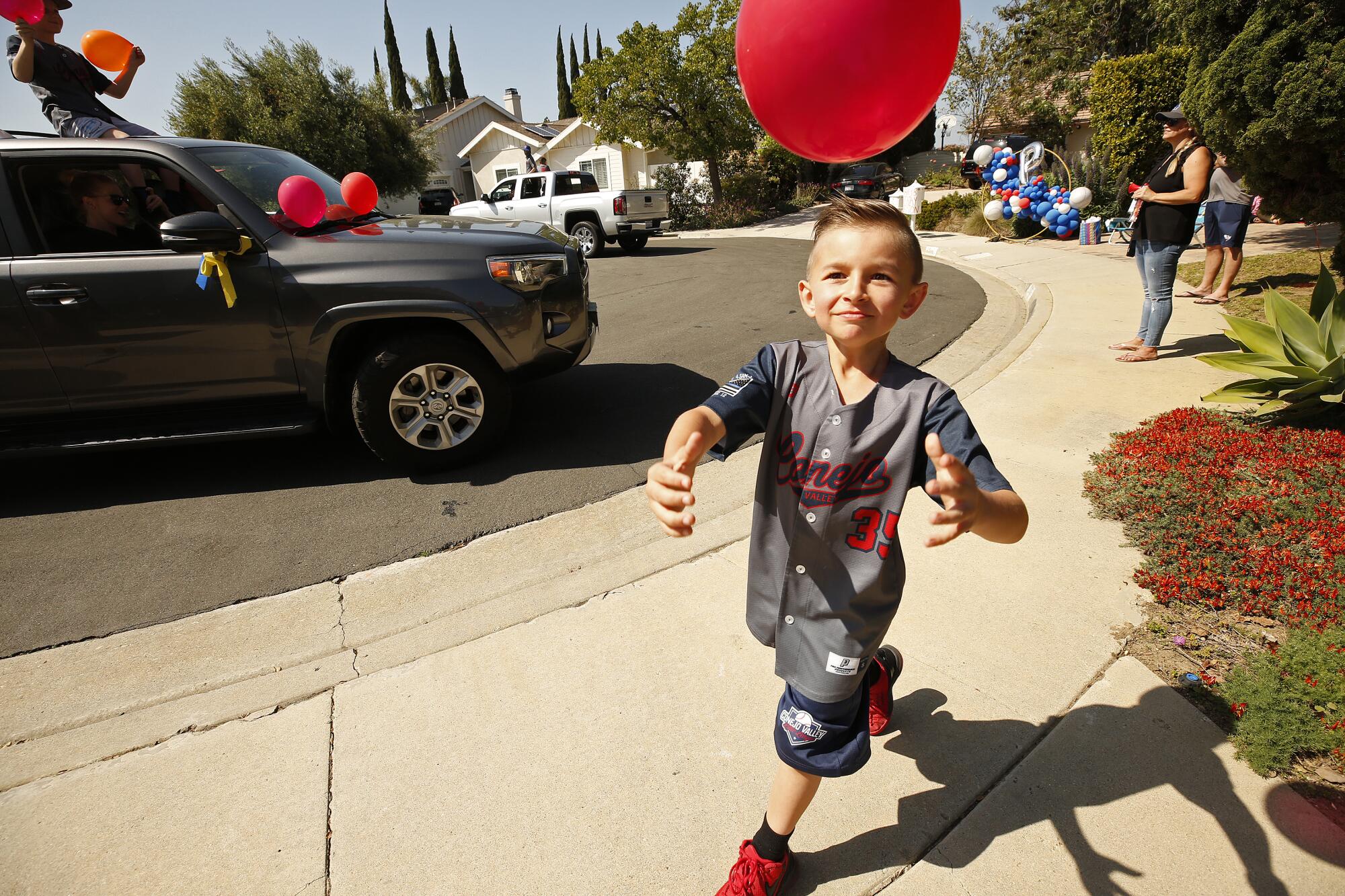 Peyton catches a balloon released from a passing vehicle filled with parents and teammates.