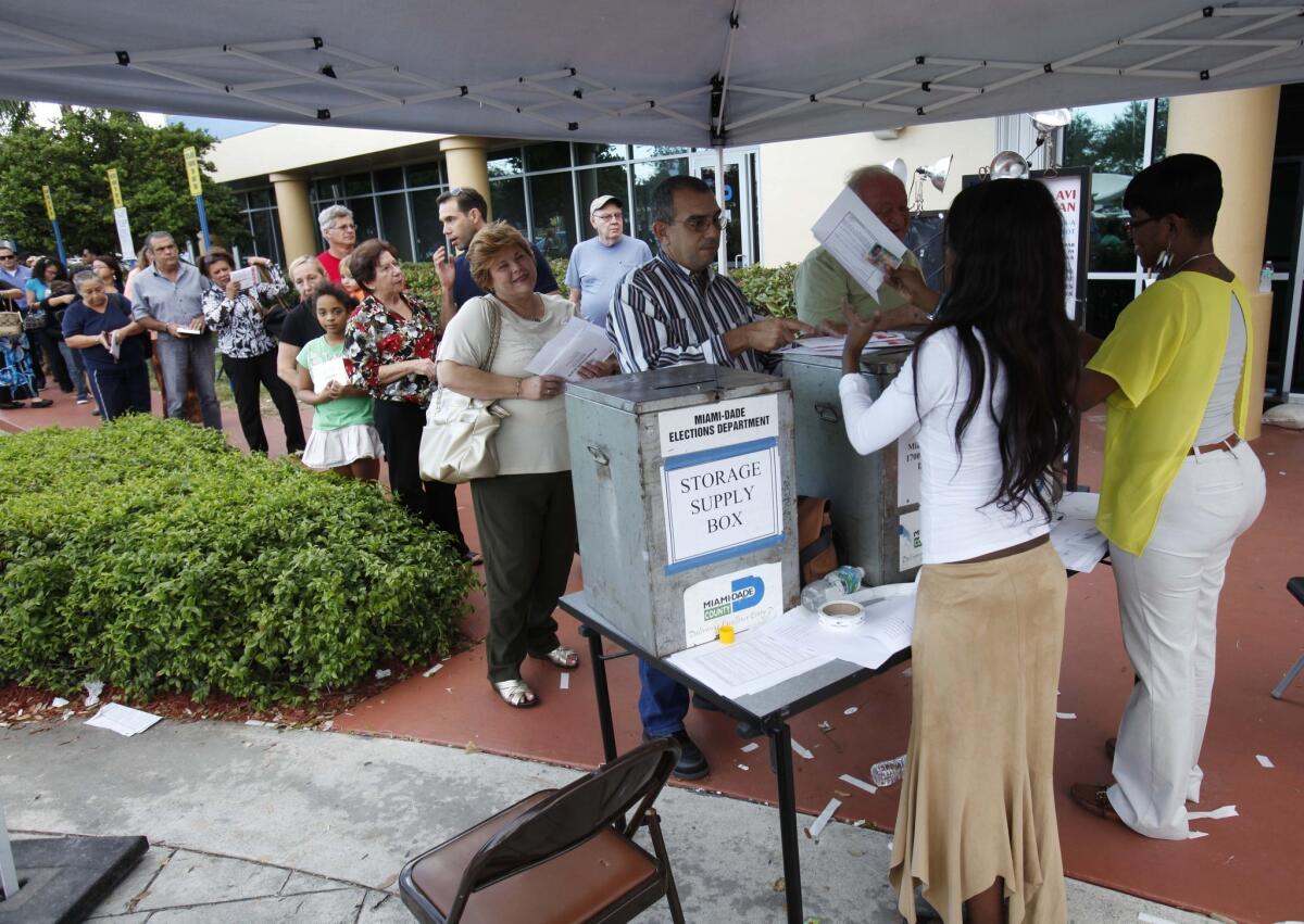 Voters line up to turn in their absentee ballots in person at the Miami-Dade County Elections Department, in Doral, Fla.