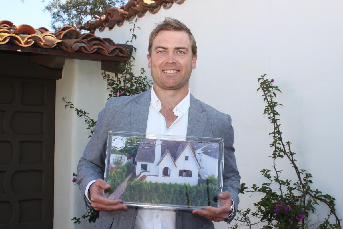 Scott Zingheim, co-owner of a house at 1237 Torrey Pines Road, holds his Jewel Award, which depicts his home.