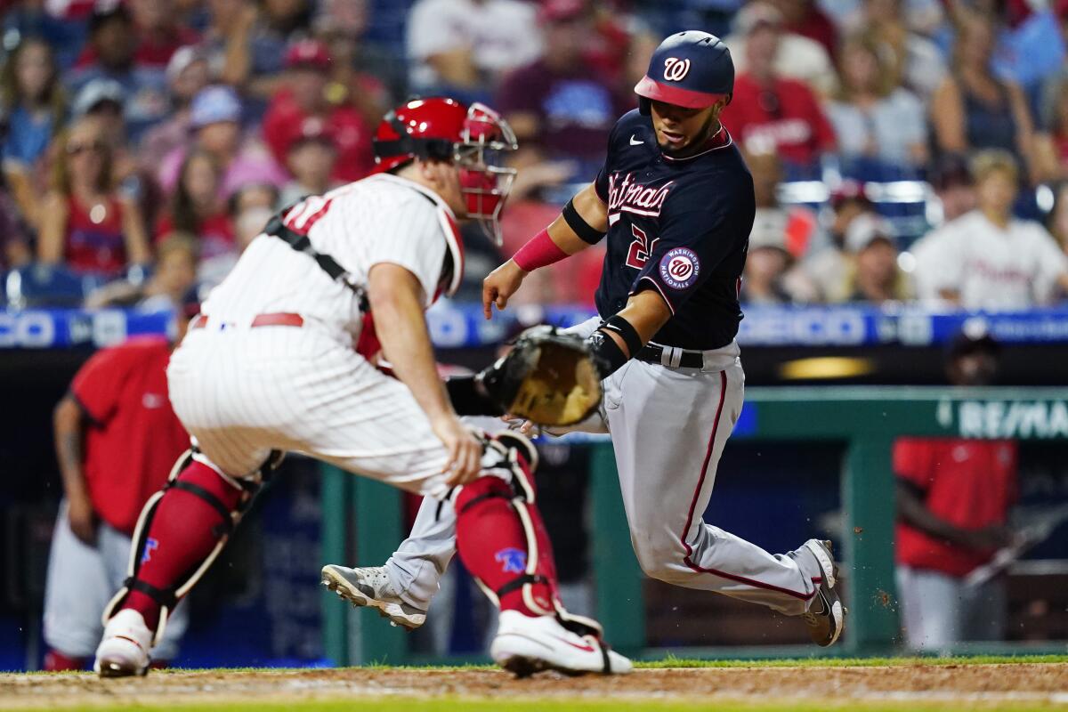 Washington Nationals' Keibert Ruiz, right, scores past Philadelphia Phillies catcher J.T. Realmuto on a two-run double by Luis Garcia during the seventh inning of a baseball game, Wednesday, July 6, 2022, in Philadelphia. (AP Photo/Matt Slocum)