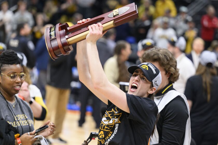 Iowa guard Caitlin Clark shows off the trophy as she celebrates after an Elite 8 college basketball game of the NCAA Tournament against Louisville, Sunday, March 26, 2023, in Seattle. Iowa won 97-83. (AP Photo/Caean Couto)
