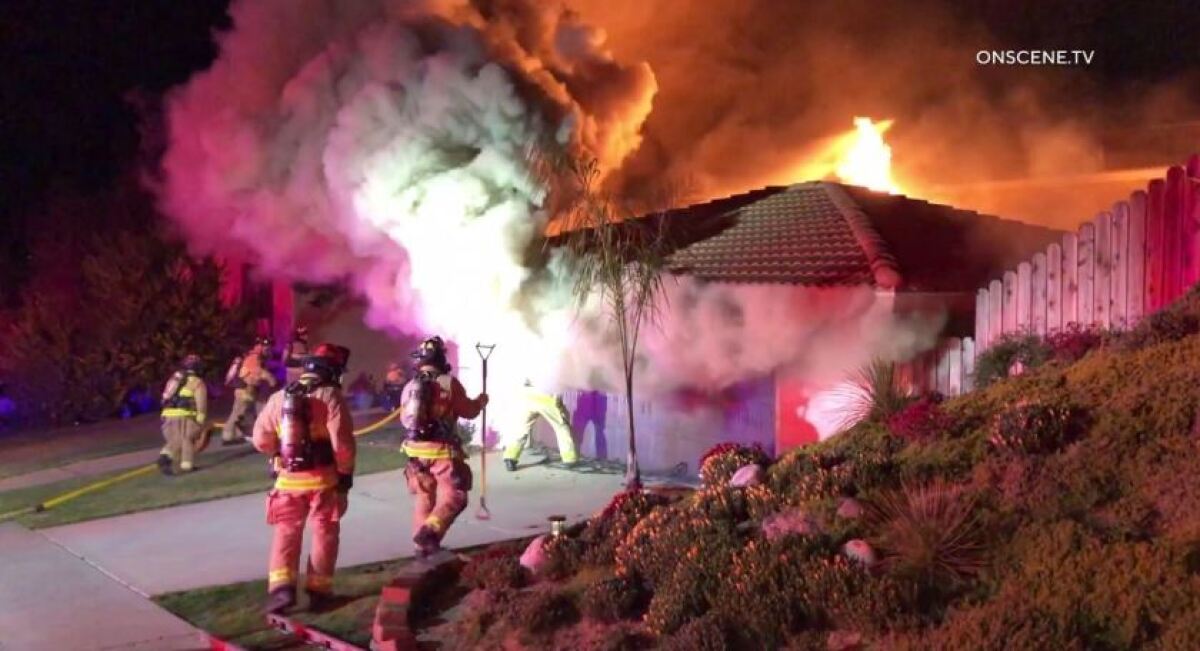 Firefighters battle flames shooting from a garage as smoke billows into the air Tuesday night on Santa Helena in Solana Beach.