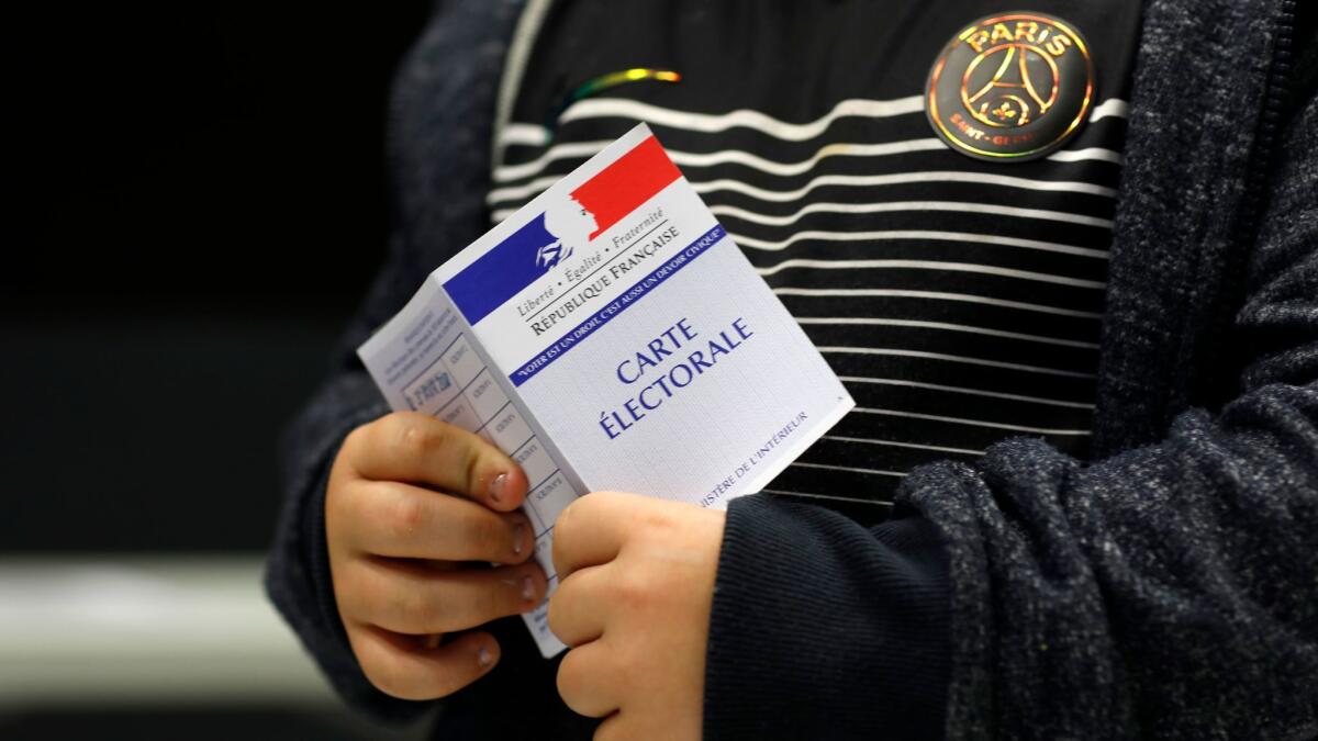 A child holds his mother's voting card on Sunday in Anthony, outside Paris.