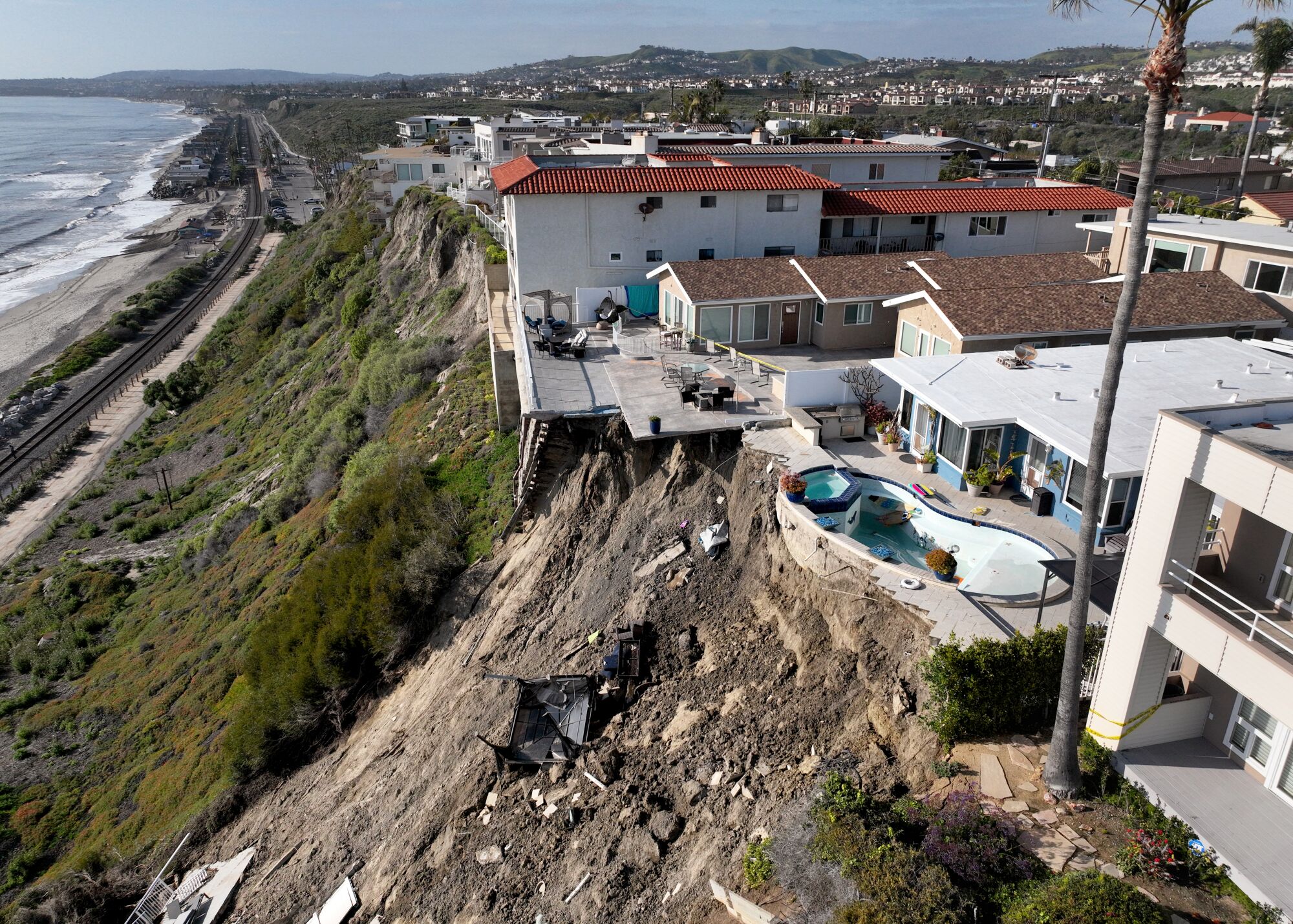 An aerial view of back yards where a mudslide eroded patio areas and exposed external structure of a pool.