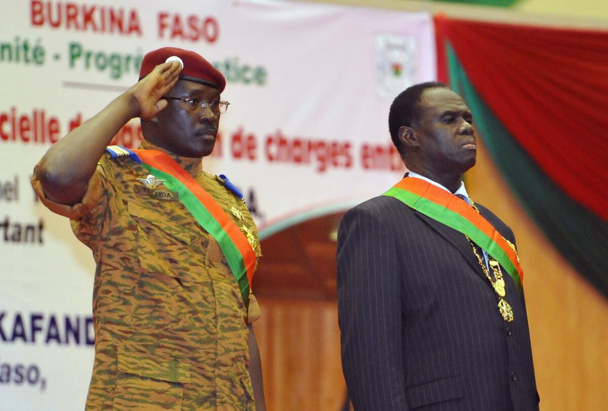 Interim President of Burkina Faso Michel Kafando, right, and Prime Minister Lt. Col. Isaac Zida, left, listen during Kafando's inauguration ceremony in 2014.