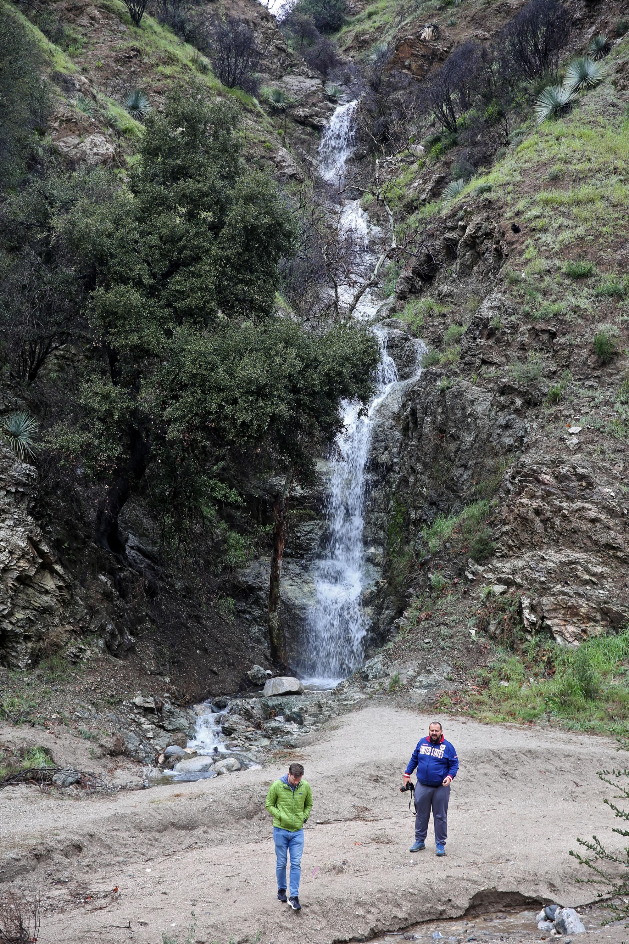 Forest visitors take photos of a temporary waterfall   along Highway 39.