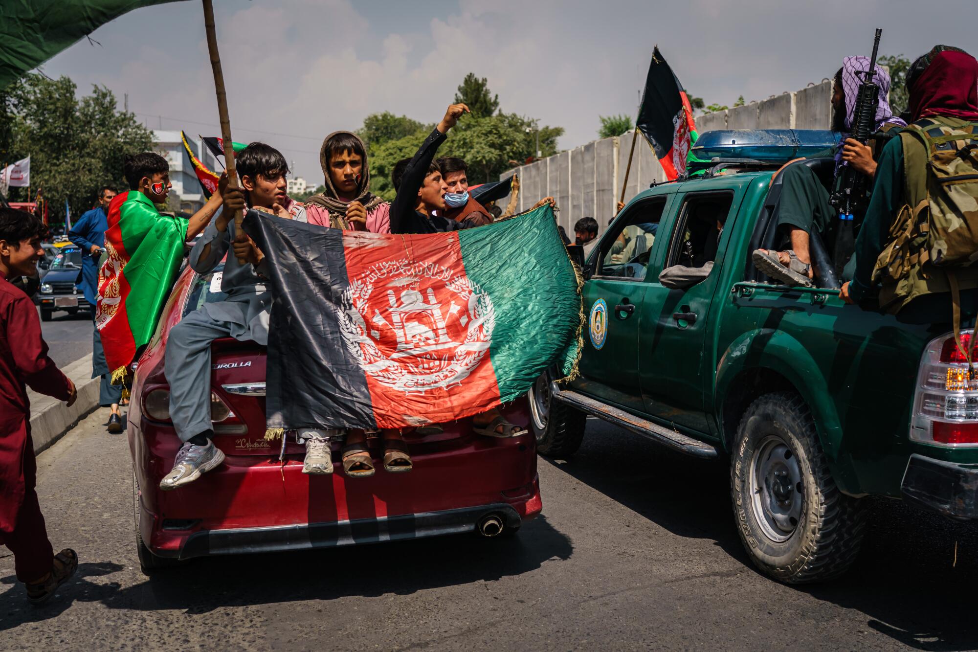 Afghans march down the street carrying banners and the flag of Afghanistan
