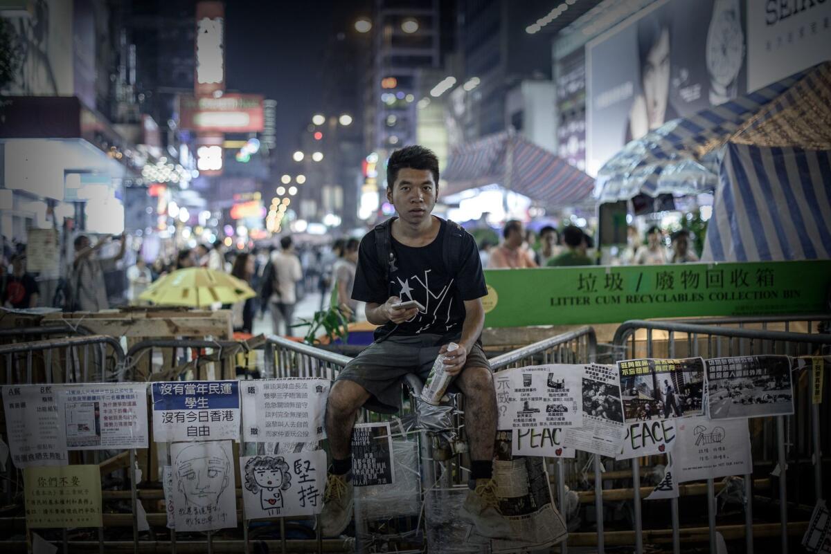 A pro-democracy protester sits on a barricade at a protest site in the Mong Kok district of Hong Kong on Oct. 26.