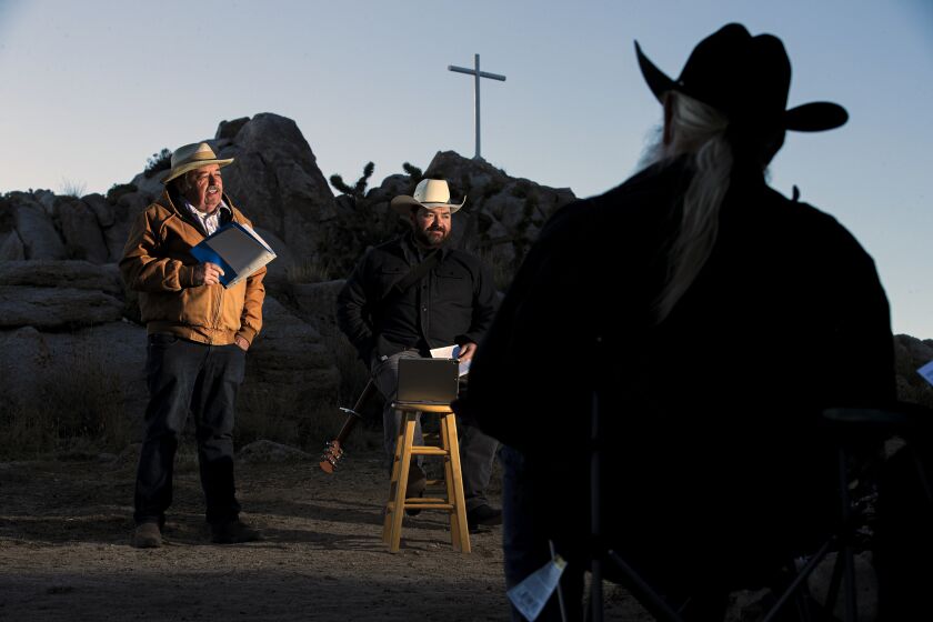 Cima, CA - April 04: Home missionary Larry Craig, left, flanked by his son Larry Craig, singing hymns, holds yearly sunrise Easter service on Sunrise Rock in the Mojave Desert White Cross World War I Memorial on Sunday, April 4, 2021 in Cima, CA.(Irfan Khan / Los Angeles Times)