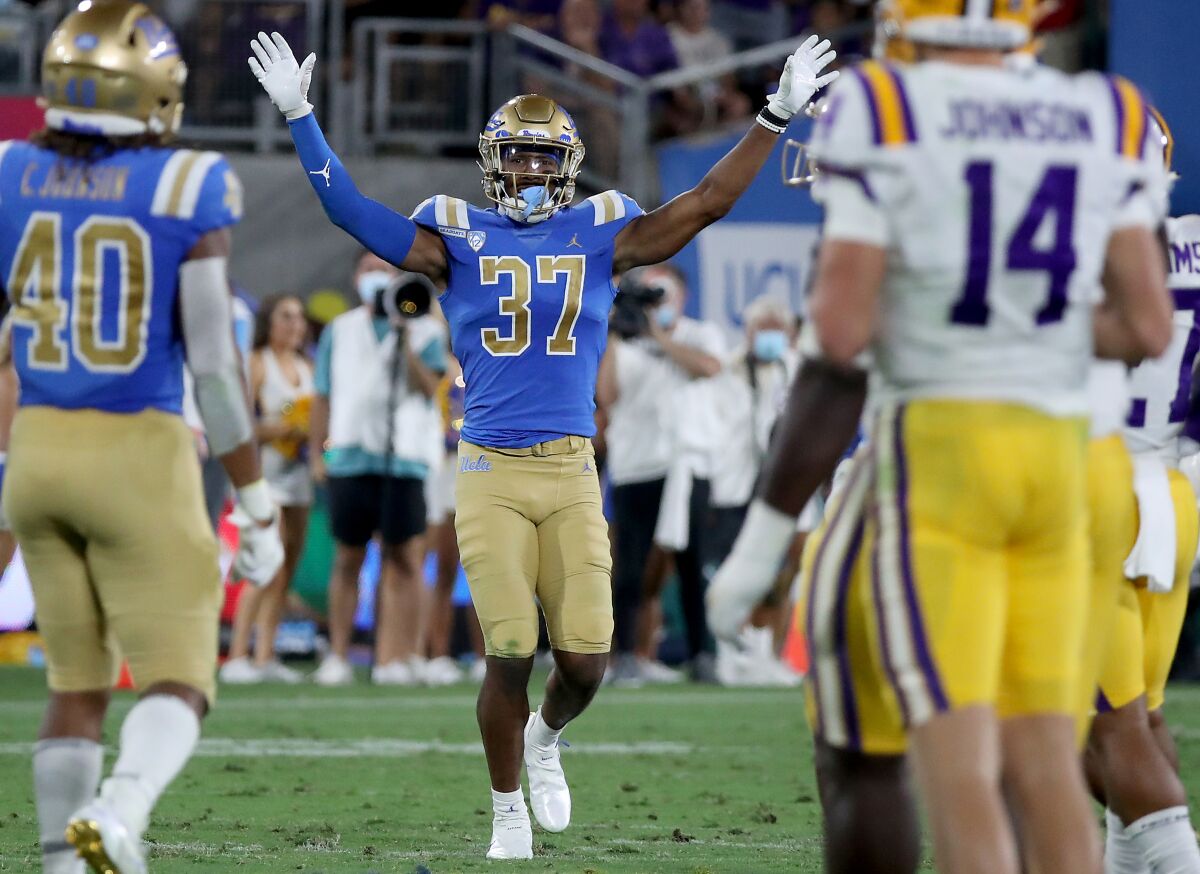 UCLA safety Quentin Lake raises his arms to signal his teammates on the field.