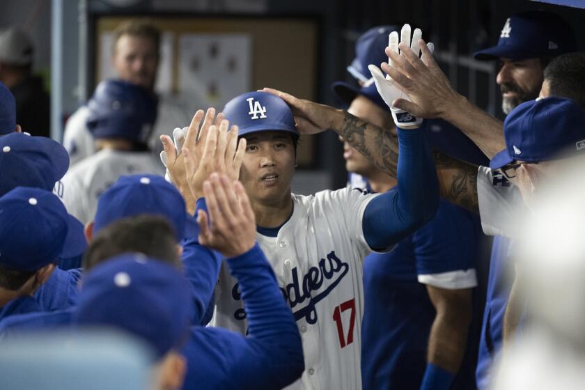 Los Angeles Dodgers' Shohei Ohtani celebrates his solo home run in the dugout during the eighth inning of a baseball game against the Philadelphia Phillies in Los Angeles, Monday, Aug. 5, 2024. (AP Photo/Kyusung Gong)