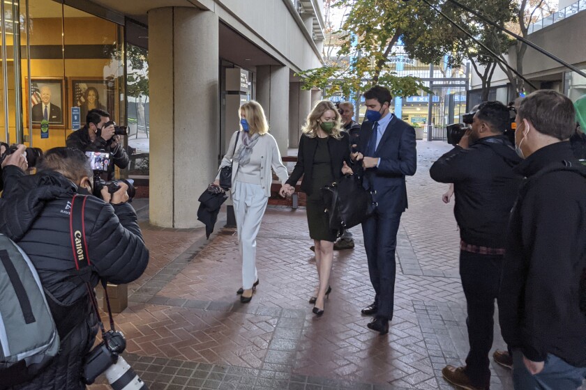 Elizabeth Holmes, center, enters the Robert F. Peckham Federal Building with her partner, Billy Evans, right, and her mother, Noel Holmes, in San Jose, Calif., on Tuesday, Dec. 7, 2021. Looking on at far right is John Carreyrou, the former Wall Street Journal reporter who wrote the October 2015 story that exposed flaws in Theranos' blood-testing technology. (AP Photo/Michael Liedtke)