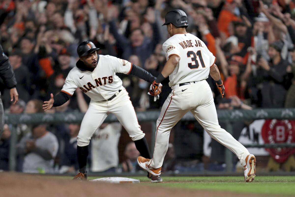 San Francisco Giants' LaMonte Wade Jr. is congratulated by first base coach Antoan Richardson after hitting a game winning single against the Arizona Diamondbacks during the ninth inning of a baseball game in San Francisco, Thursday, Sept. 30, 2021. (AP Photo/Jed Jacobsohn)