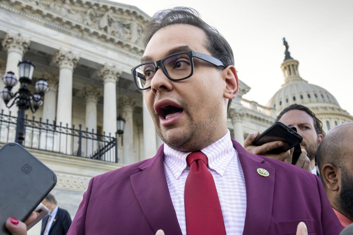 George Santos, in a purple jacket and maroon tie, speaks to reporters outside the Capitol