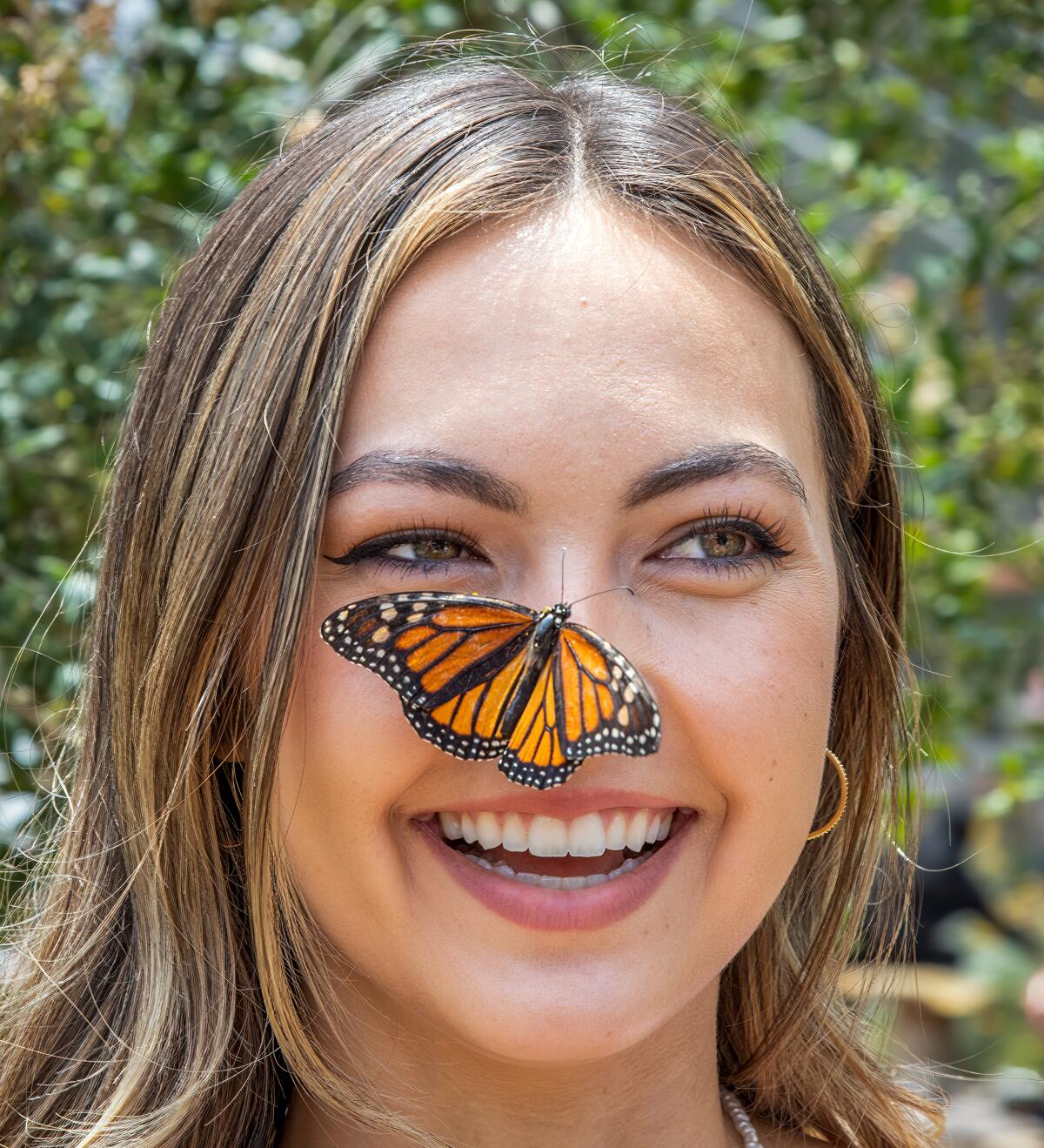 A monarch butterfly lands on Maylie Schreck's nose during her visit to Butterfly Farms in Encinitas.
