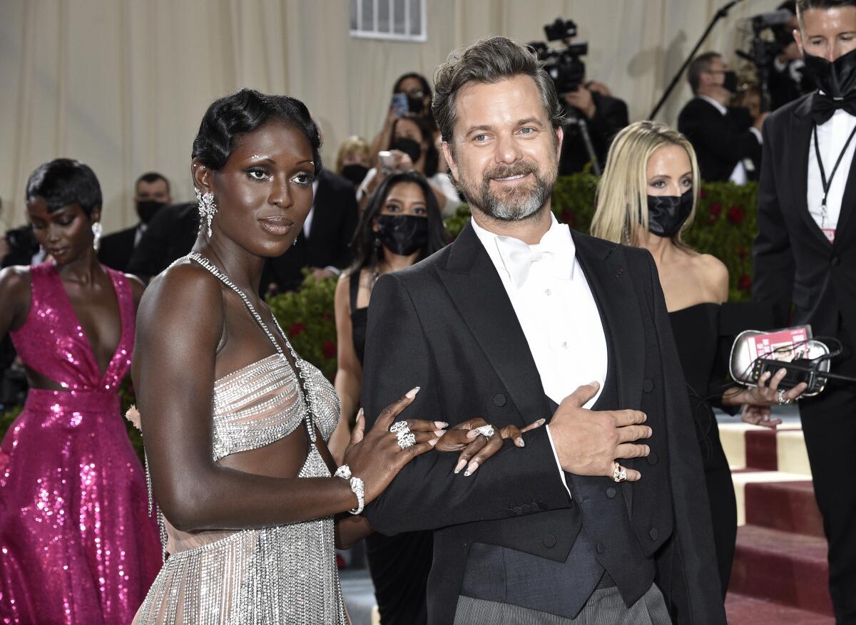 Jodie Turner-Smith in a metallic cut-out gown holding the arm of a tuxedo-clad Joshua Jackson