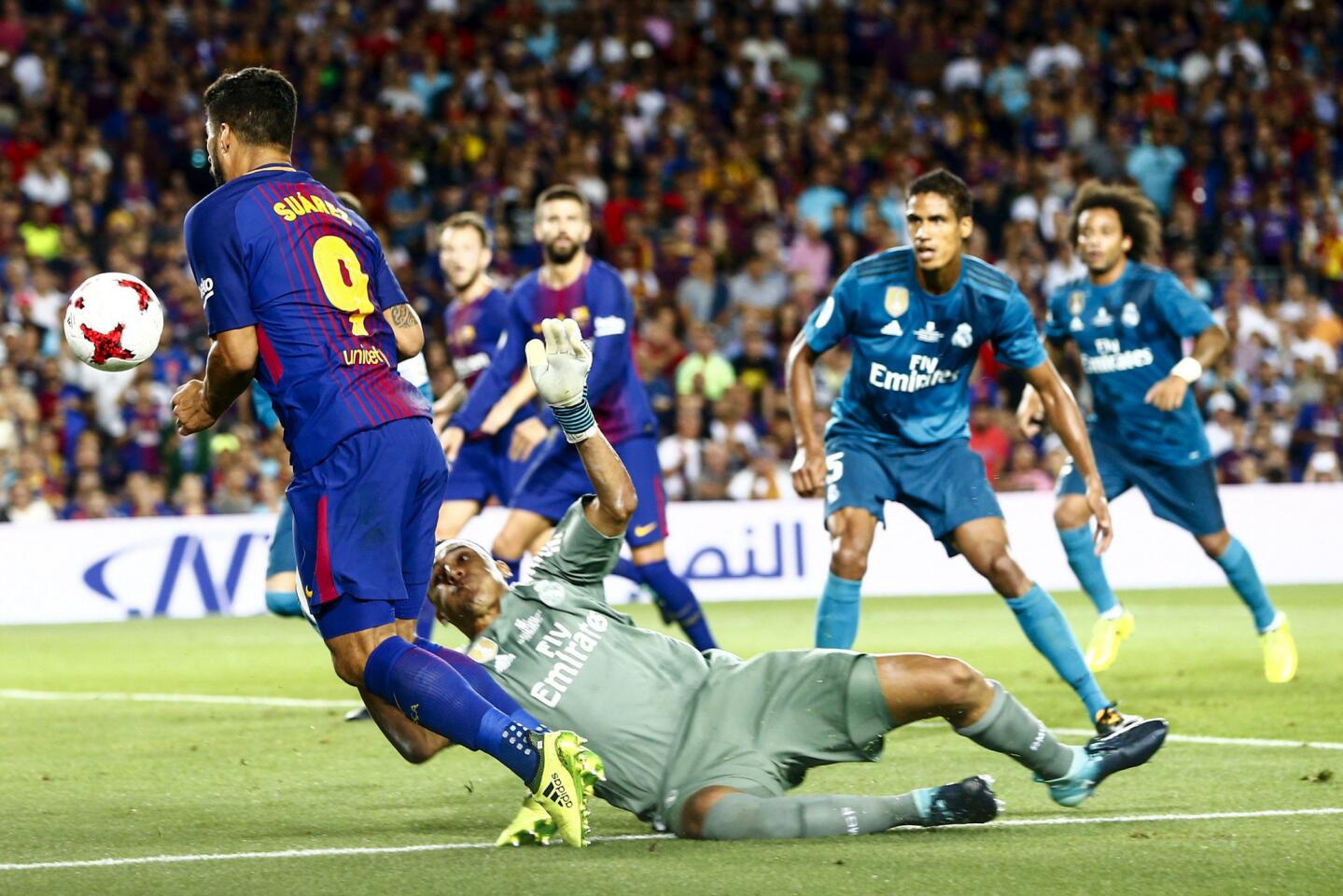 El delantero uruguayo del Barcelona Luis Suárez (i) cae ante la salida del portero costarricense del Real Madrid Keylor Navas (2i) y el árbitro señaló penalti. EFE