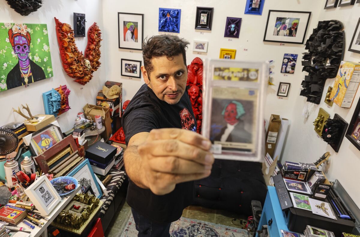 Artist Isaac Coronado shows one of his upcycled collectible cards in his Barrio Logan studio.