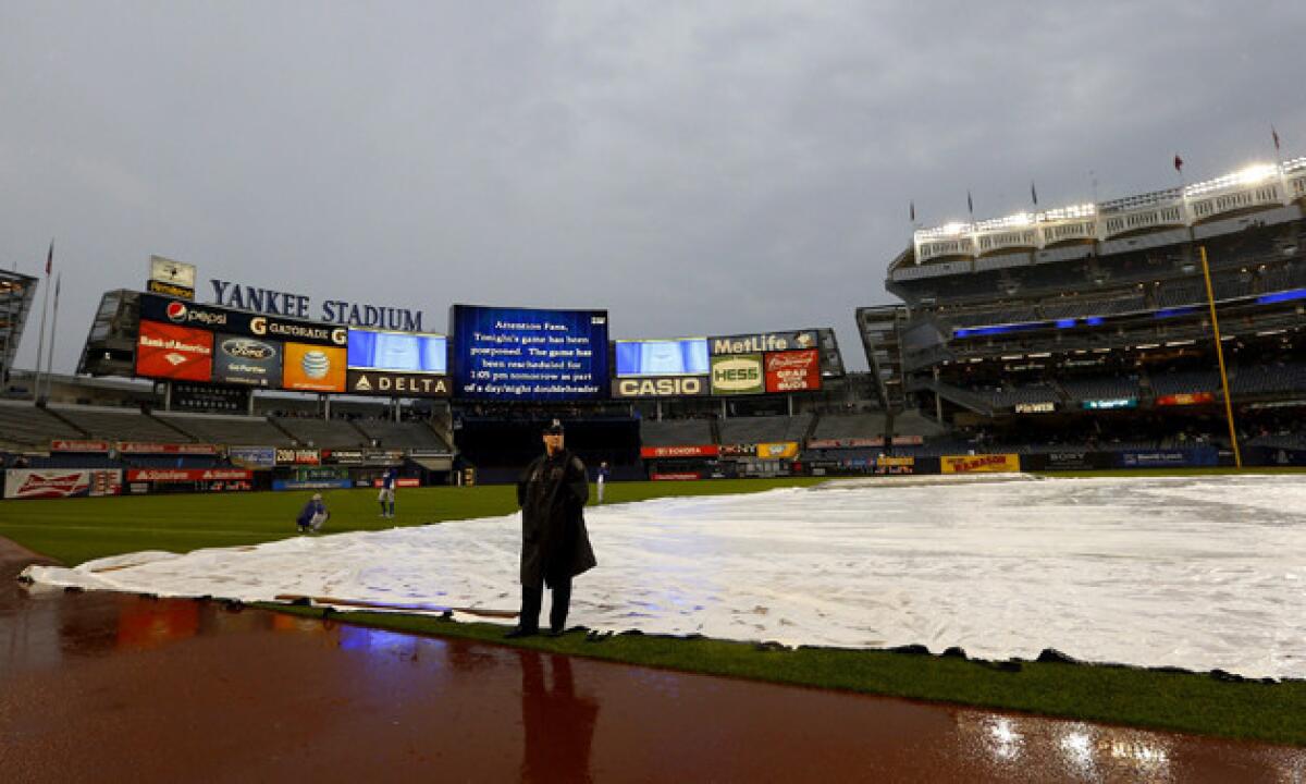 A New York City Police officer stands on the field of rain-soaked Yankee Stadium on Tuesday.