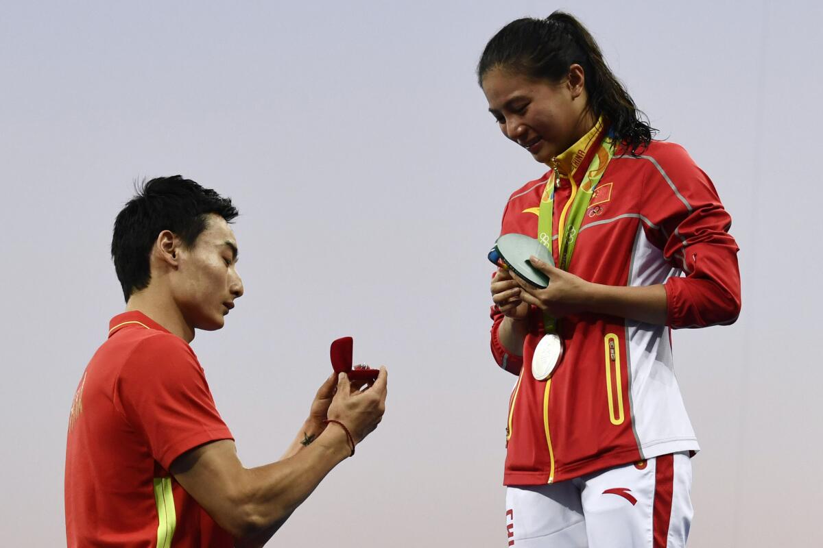 Chinese silver medal-winning diver He Zi, right, receives a marriage proposal from countryman Qin Kai, also a diver, during the podium ceremony for the women's diving three-meter springboard final Sunday.