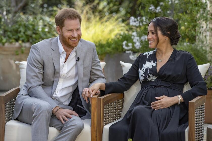 Esta imagen proporcionada por Harpo Productions muestra al príncipe Enrique, a la izquierda, y a Meghan, duquesa de Sussex, hablando sobre el bebé que esperan durante una entrevista con Oprah Winfrey. (Joe Pugliese/Harpo Productions via AP)
