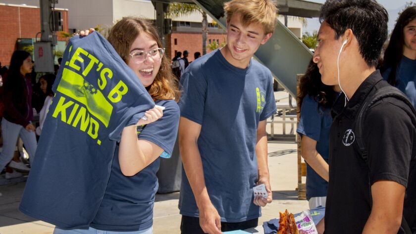 Caitlyn Roum and Aubrey Sicrent enthusiastically offer an event T-shirt to Denilson Lopez during Let’s Be Kind Day held Thursday at Costa Mesa Middle and High schools.