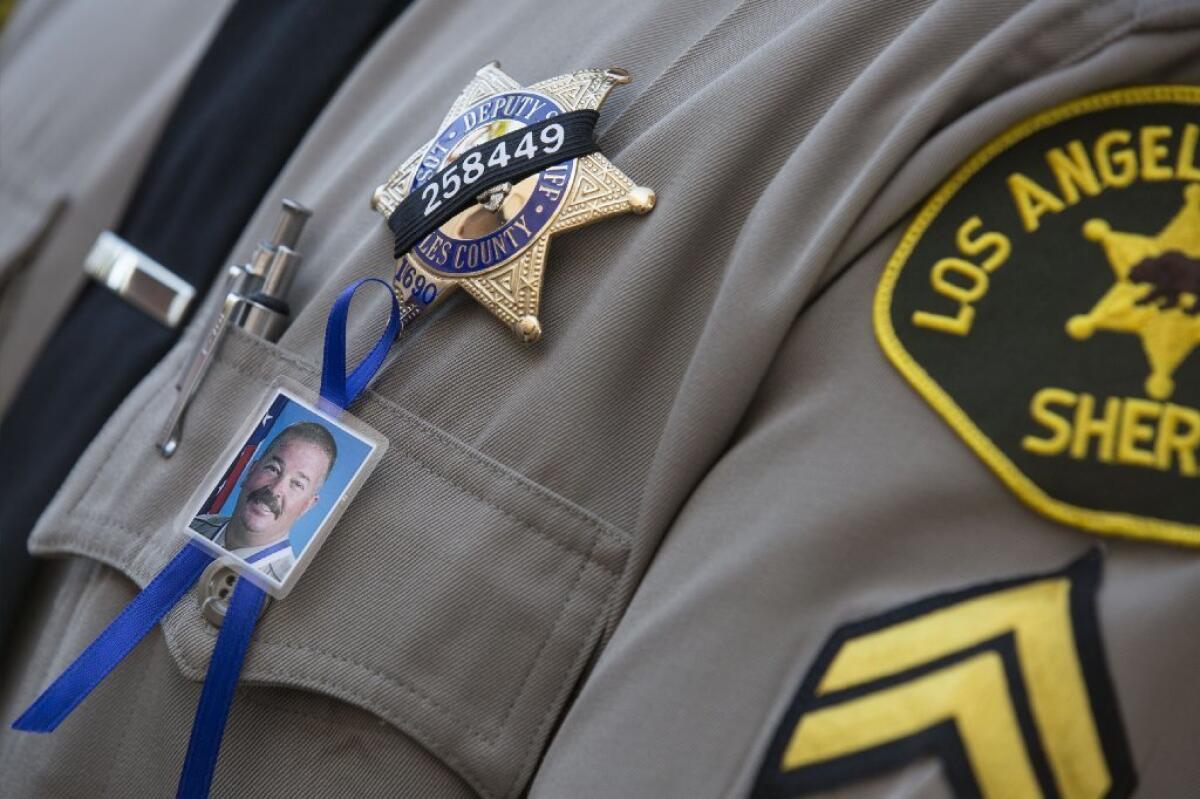 A Los Angeles County sheriff's deputy wears a picture of Sgt. Steve Owen, who was gunned down in Lancaster last month. The Sheriff's Department has arrested five people and accused them of helping the gunman evade capture.