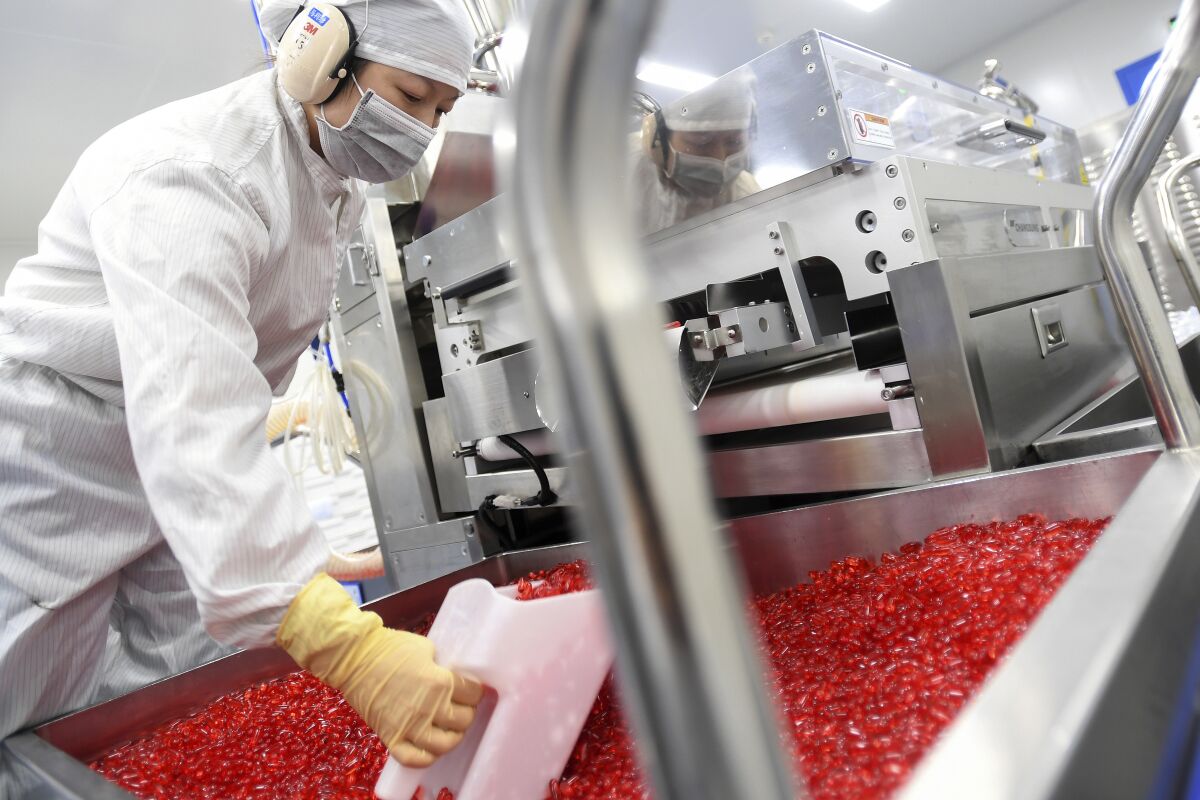 A worker scoops soft gels at Humanwell PuraCap Pharmaceuticals, a major Chinese soft gel pharmaceutical manufacturer, in Wuhan in central China's Hubei province on Oct. 25, 2021. China's manufacturing activity contracted for a second straight month in October amid a materials shortage and a widespread power crunch. (Chinatopix Via AP)
