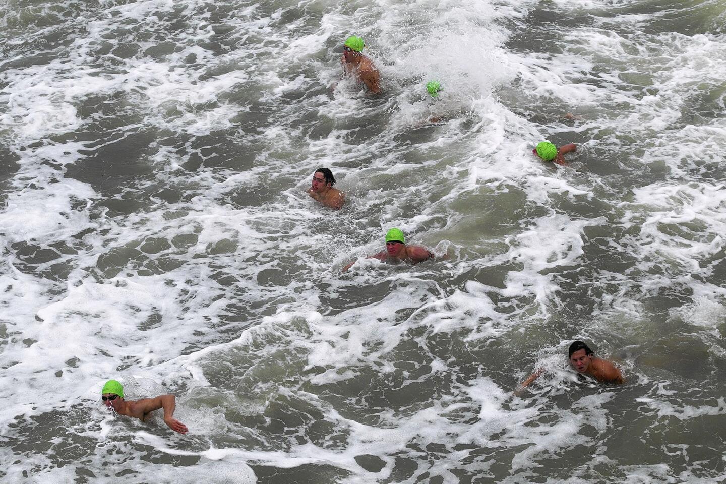 Candidates swim next to the pier during the city of Huntington Beach's ocean lifeguard tryouts on Saturday.