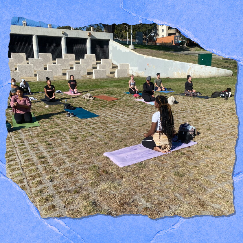 Die Leute sitzen draußen auf Yogamatten.