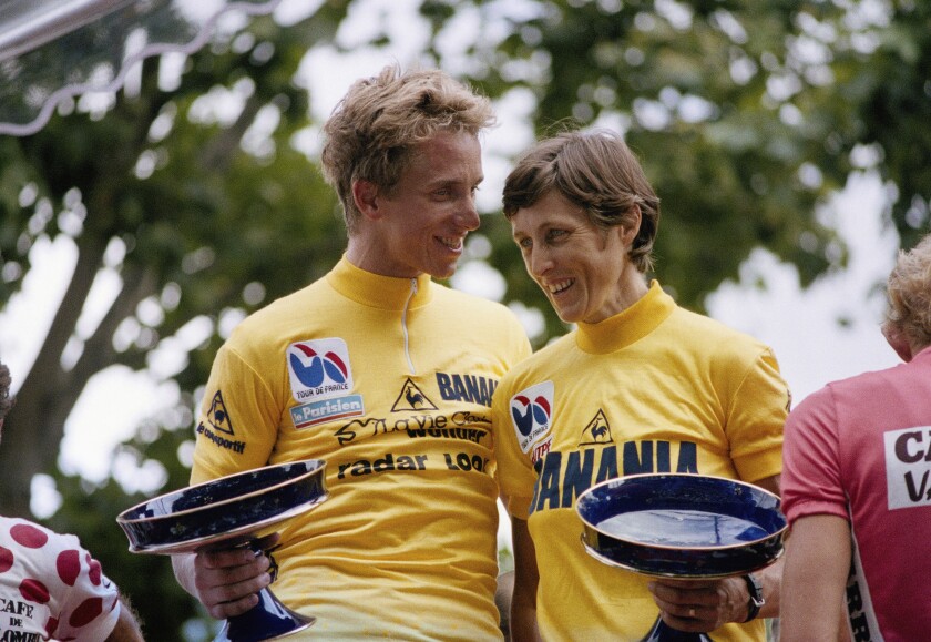 FILE - In this Sunday, July 27, 1986 file photo, Tour de France winners Italian Maria Canins and American Greg Lemond after the arrival of the two races on the Champs Elysees in Paris. A women's version of the Tour de France will be held in 2022 with a start on Paris' iconic Champs-Elysees boulevard after the conclusion of the men's race, organizers announced Thursday June 17, 2021. (AP Photo/Lionel Cironneau, File)