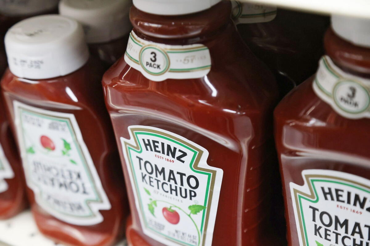 Bottles of Heinz ketchup on a shelf.