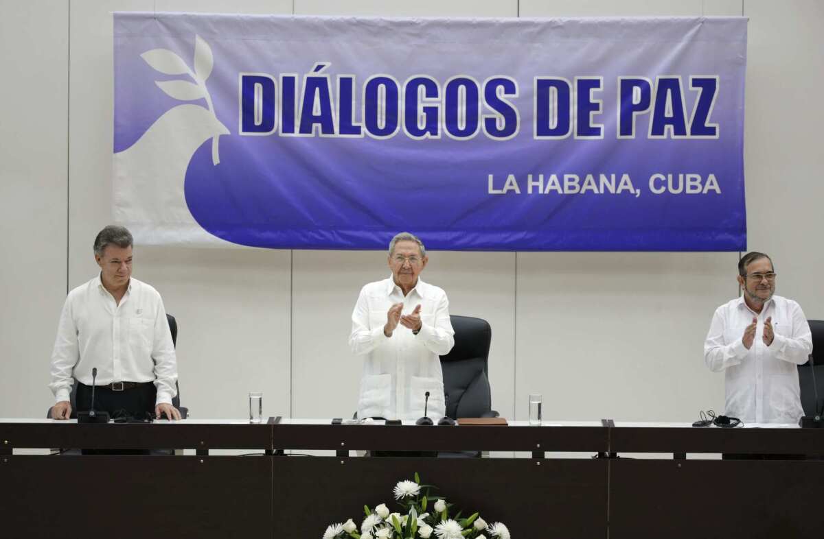 El presidente de Colombia Juan Manuel Santos, a la izquierda, de Cuba Raúl Castro, en el centro, y el comandante de las Fuerzas Armadas Revolucionarias de Colombia (FARC) "Timoleón Jiménez" asisten a la ceremonia de la firma de un acuerdo de cese del fuego bilateral y definitvo y de desarme de los rebeldes en La Habana, el jueves 23 de junio de 2016. (AP Foto/Ramón Espinosa)